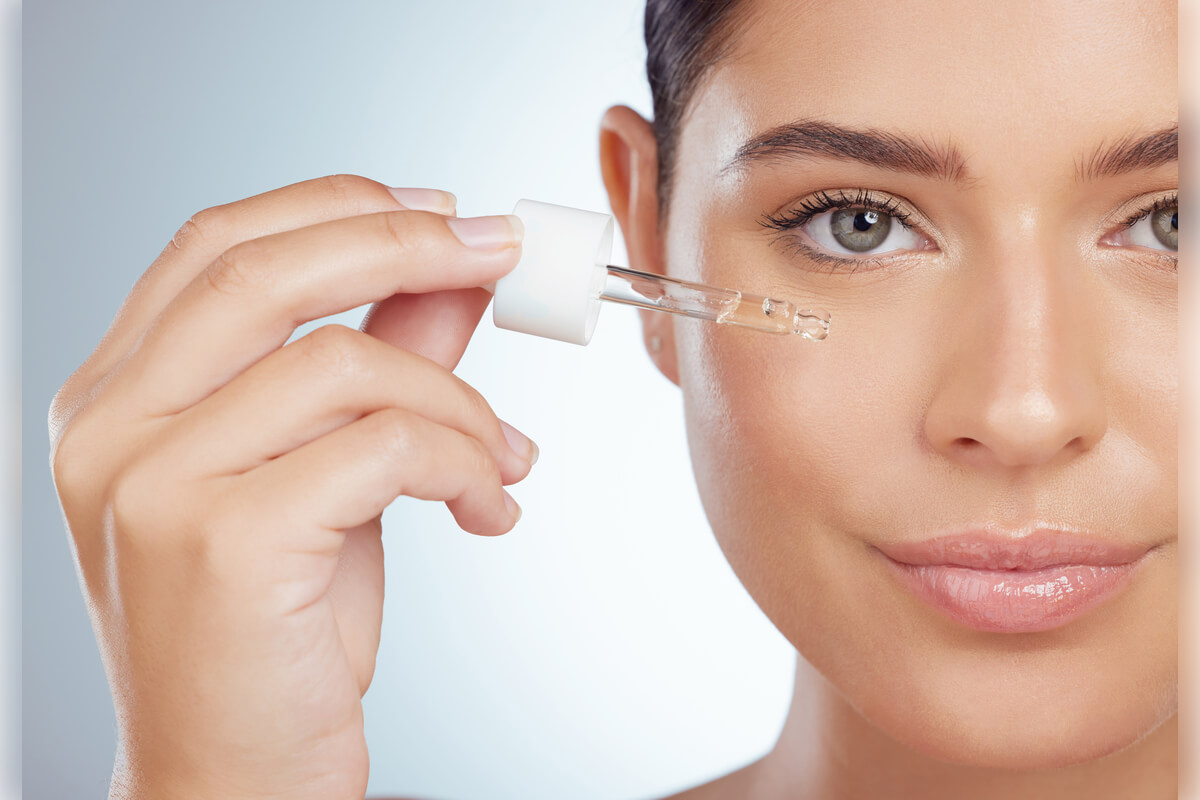 Anti-Ageing Skincare - A close-up image of a woman applying an anti-ageing serum to her face using a dropper. The focus is on her flawless, glowing skin, suggesting a well-maintained skincare routine. The woman’s expression is serene, reflecting a sense of self-care and beauty. The dropper contains a clear, serum-like substance, indicating its use for hydrating, firming, and reducing the appearance of fine lines and wrinkles. The soft, neutral background emphasizes the simplicity and effectiveness of the anti-ageing skincare product, which is likely formulated with ingredients to enhance skin elasticity and promote a youthful appearance.